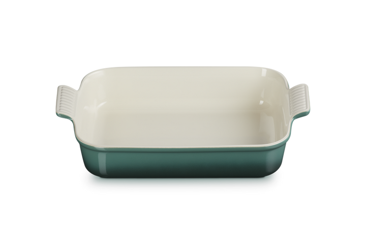 Rectangular ceramic baking dish with green base and white top on a white background
