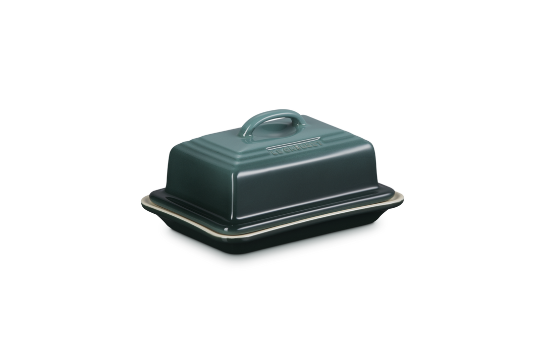 Green ceramic butter dish with lid on a white background