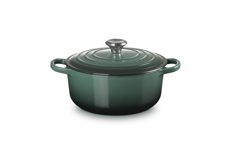 Green enameled cast iron Dutch oven with lid on a white background