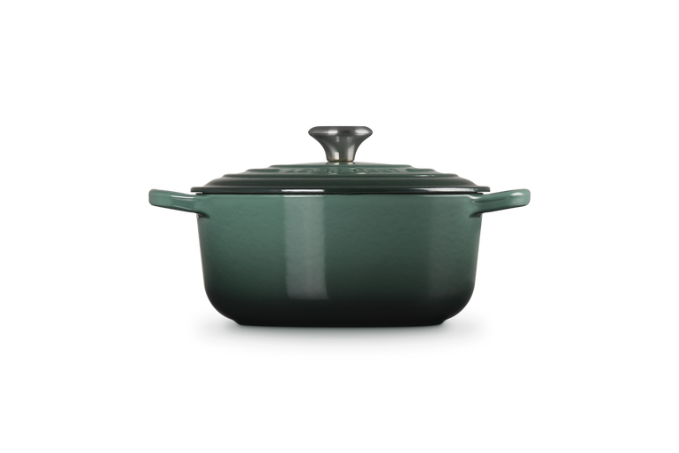 Green enameled cast iron Dutch oven with lid on a white background