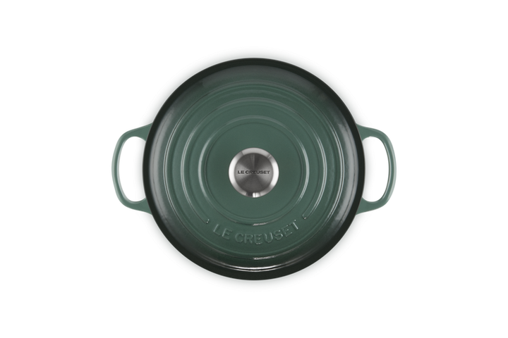 Green cast iron cookware with Le Creuset logo on a white background