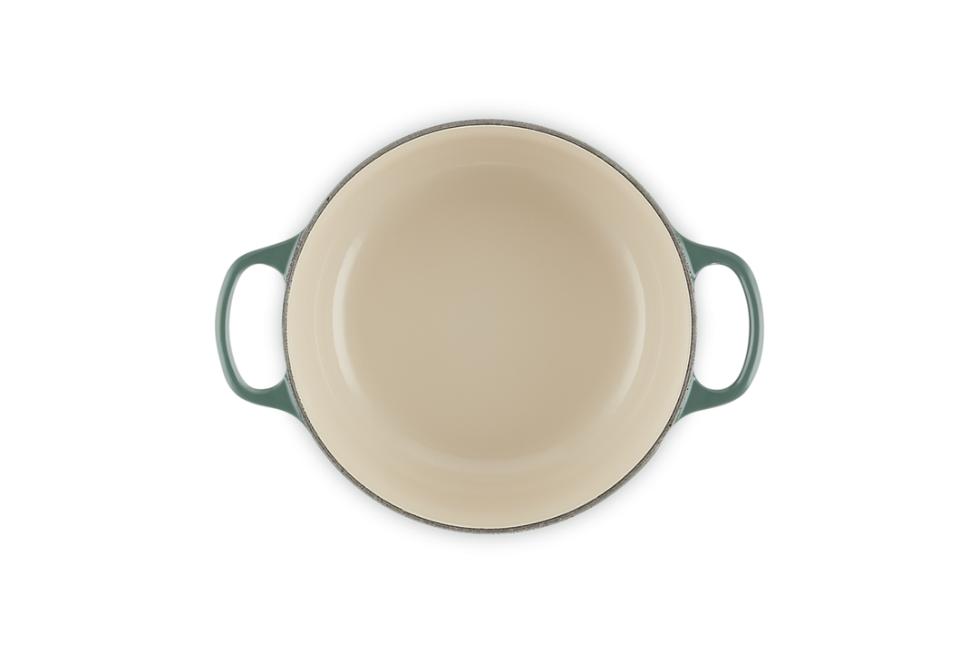 Round ceramic dish with green handles on a white background