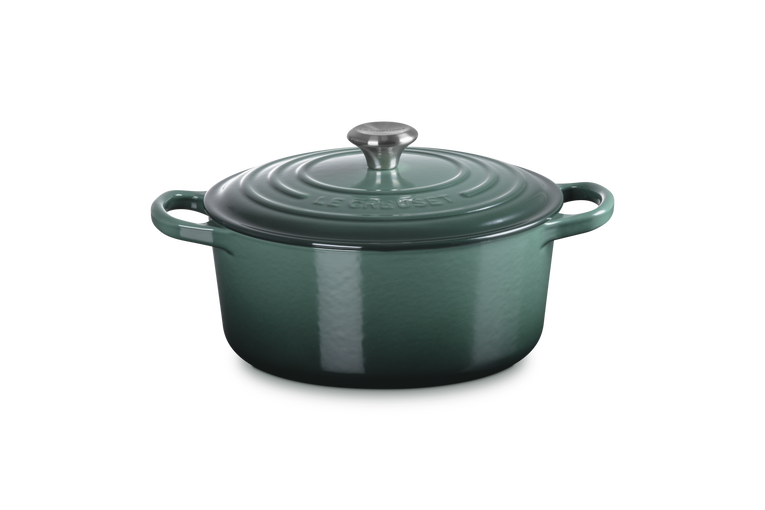 Green enameled cast iron Dutch oven with lid on a white background