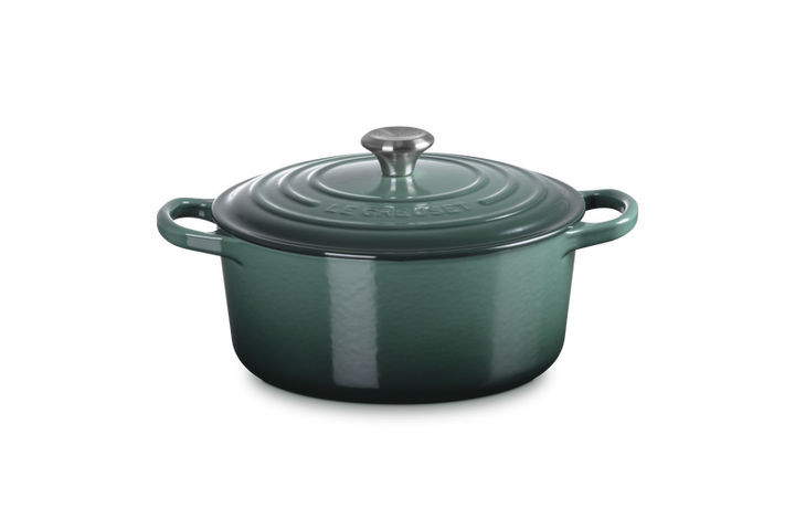 Green enameled cast iron Dutch oven with lid on a white background