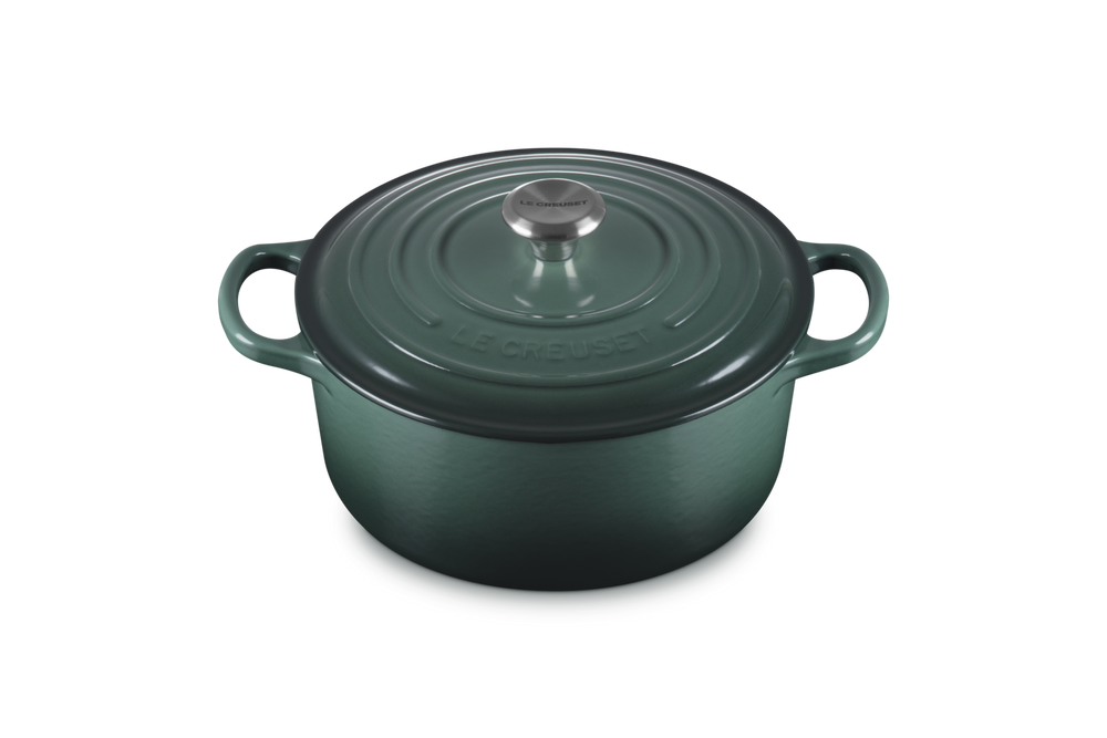 Green cast iron cookware pot with lid on a white background
