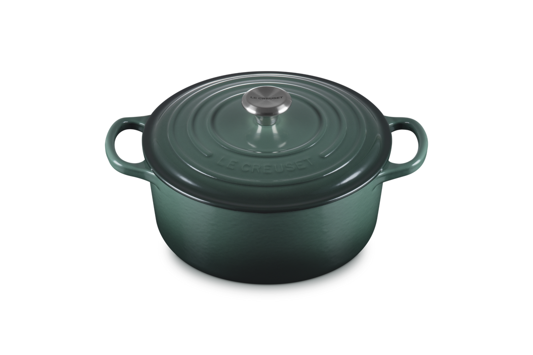 Green cast iron cookware pot with lid on a white background