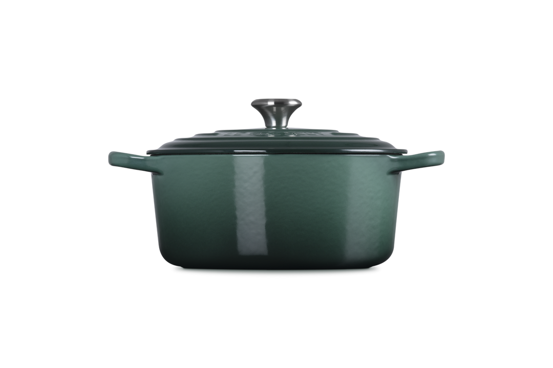 Green enameled cast iron Dutch oven on a white background