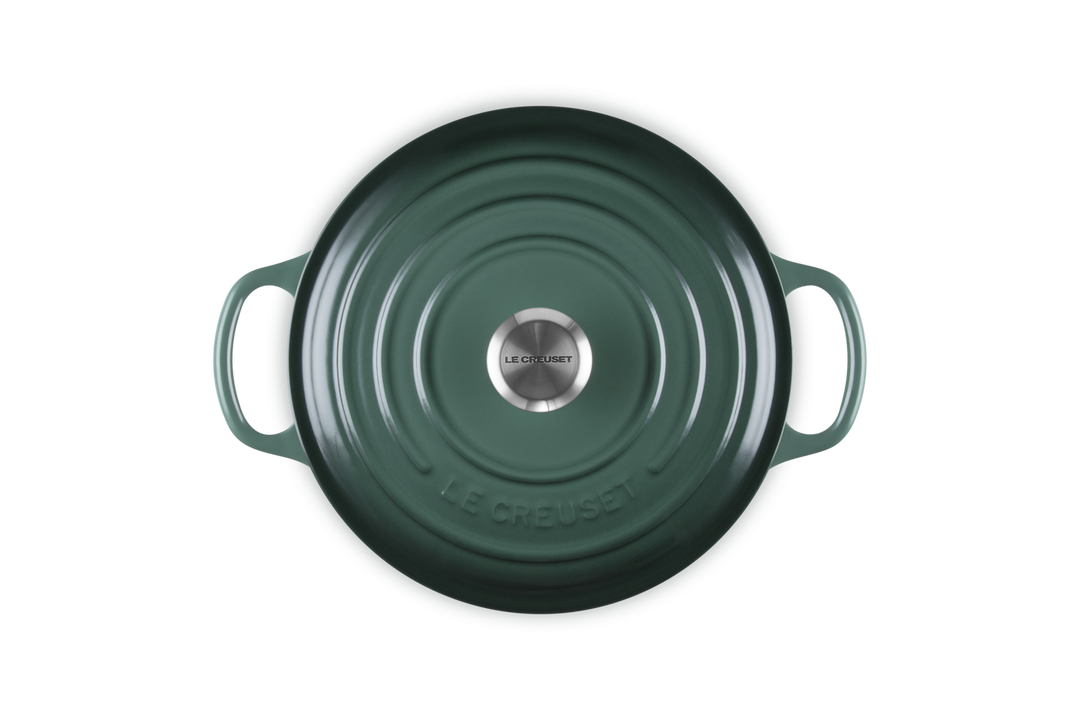 Green cast iron cookware with 'Le Creuset' branding on a white background