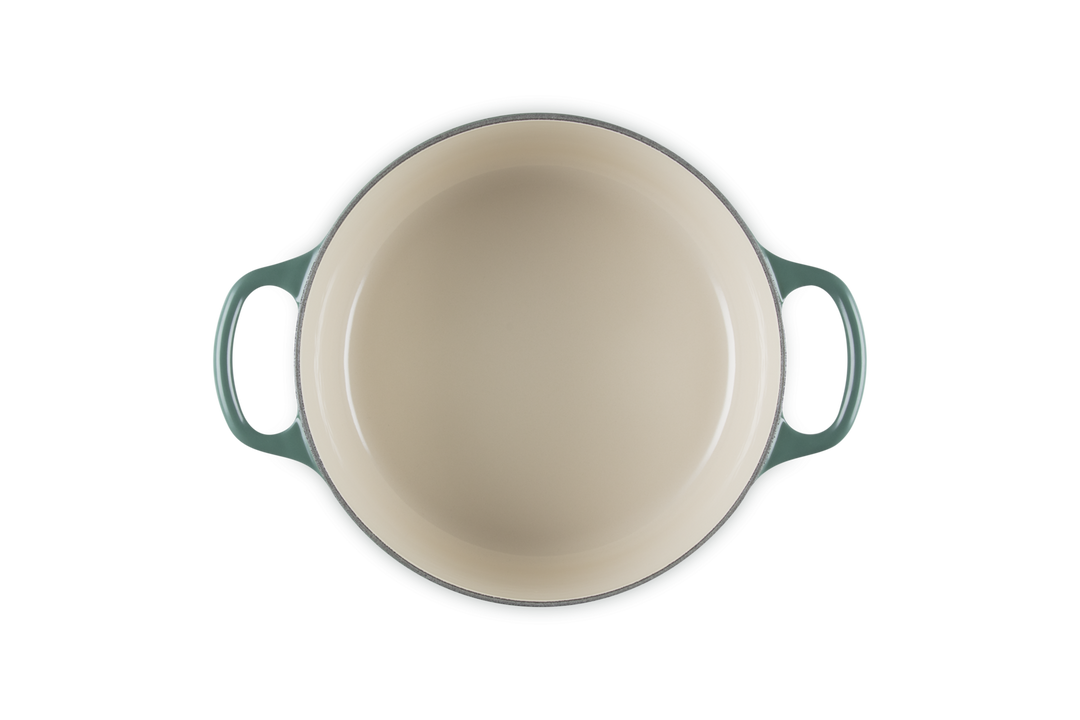 Round dish with green handles on a white background