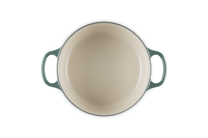 Round dish with green handles on a white background