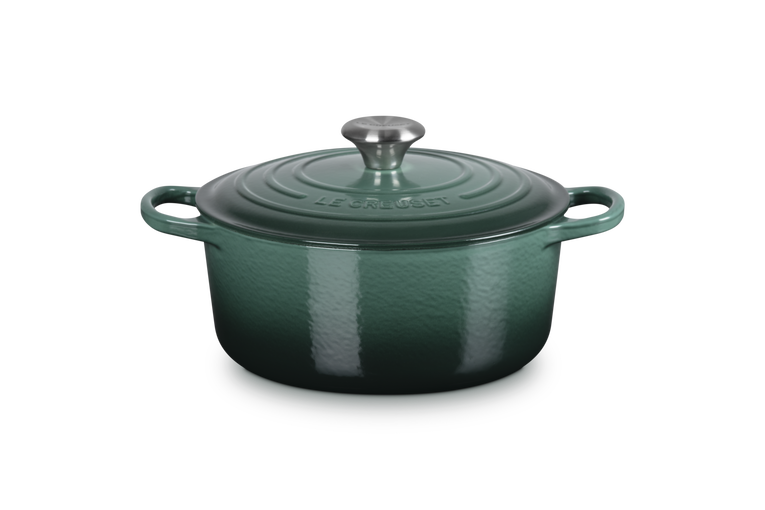Green enameled cast iron Dutch oven with a lid on a white background