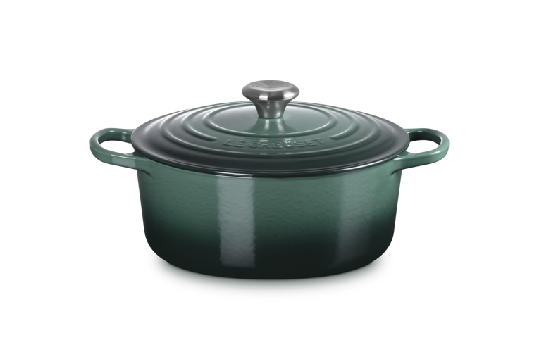 Green enameled cast iron Dutch oven with lid on a white background