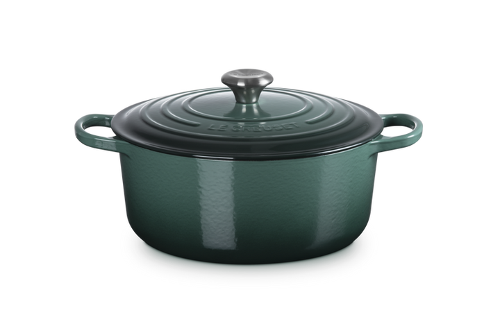 Green enameled cast iron Dutch oven with lid on a white background