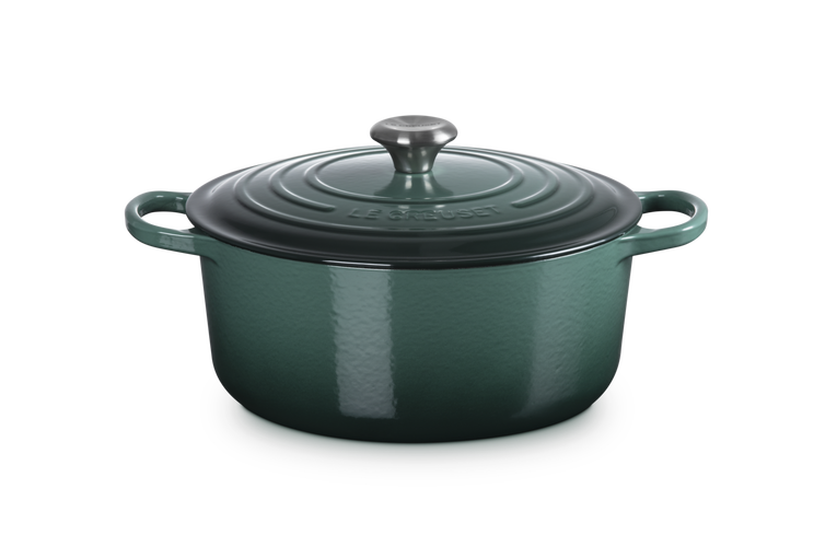 Green enameled cast iron Dutch oven with lid on a white background