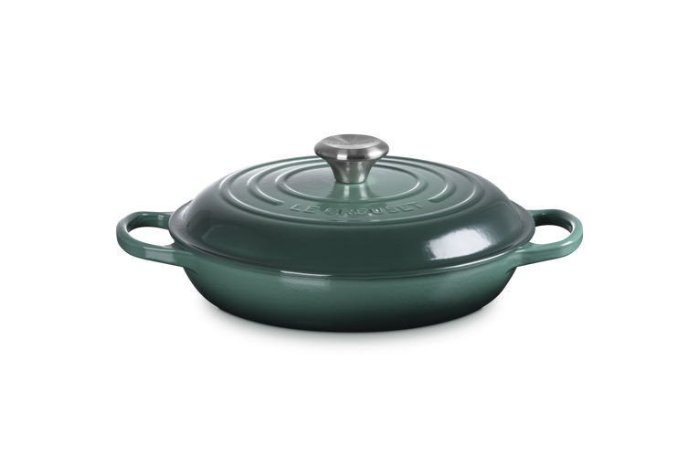 Green cast iron cookware with lid on a white background