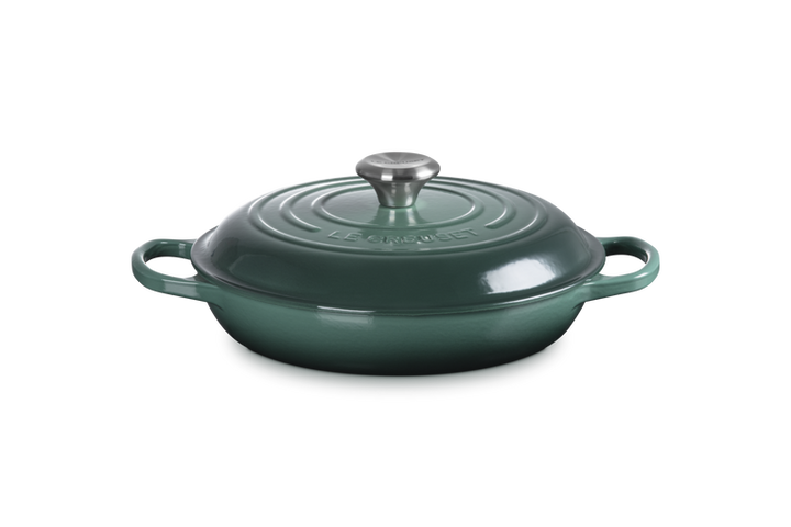 Green cast iron cookware with lid on a white background