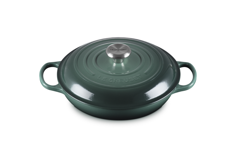 Green cast iron cookware pot with lid on a white background