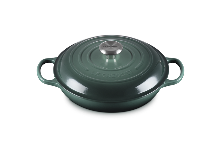 Green cast iron cookware pot with lid on a white background