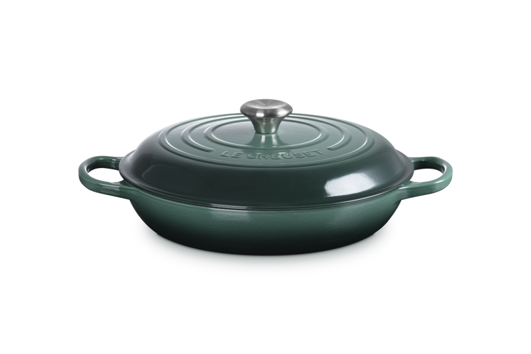Green cast iron casserole dish with lid on a white background