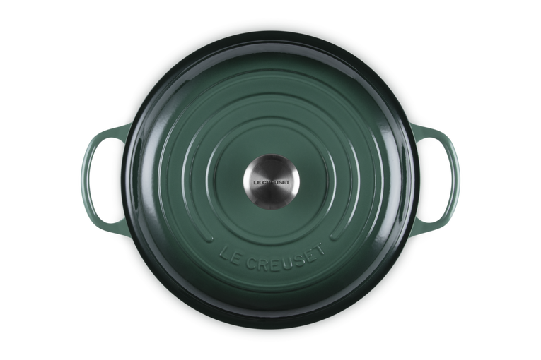 Green Le Creuset cookware lid on a white background