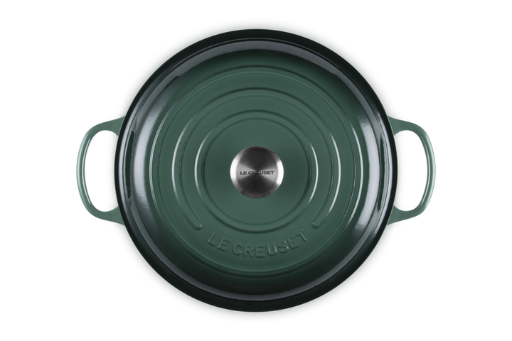 Green Le Creuset cookware lid on a white background