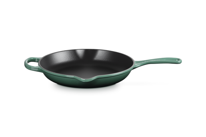 Green frying pan with black interior on a white background