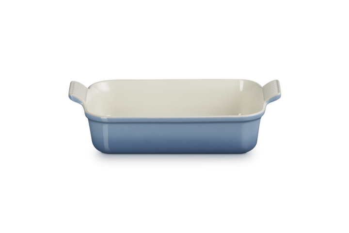 Rectangular ceramic baking dish with blue exterior and white interior on a white background
