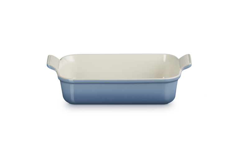 Rectangular ceramic baking dish with blue exterior and white interior on a white background