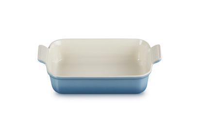 Rectangular ceramic baking dish with blue bottom and beige top on a white background