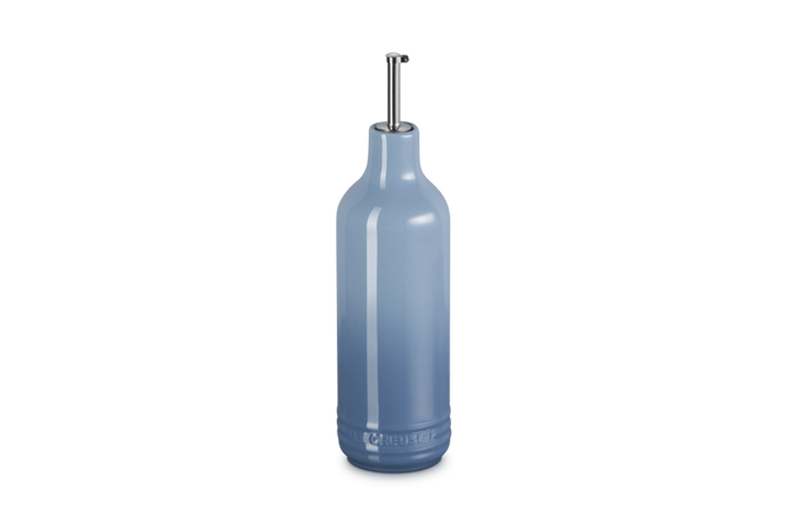 Light blue ceramic oil bottle with a metallic cap on a white background