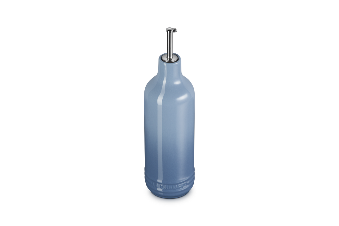 Light blue ceramic oil bottle with a metallic cap on a white background