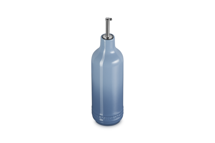 Light blue ceramic oil bottle with a metallic cap on a white background