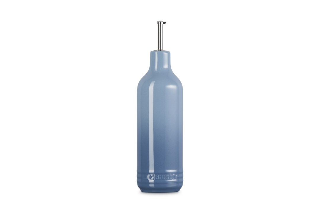 Light blue ceramic oil bottle with a metallic cap on a white background