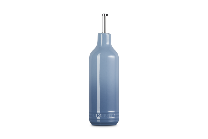 Light blue ceramic oil bottle with a metallic cap on a white background