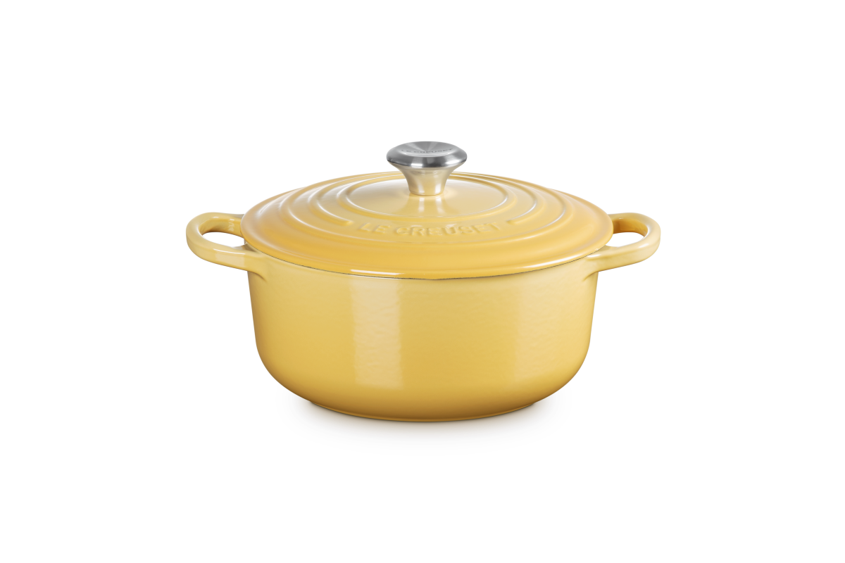 Yellow cast iron casserole with a silver knob on a white background