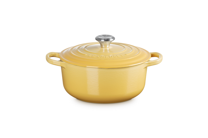 Yellow cast iron casserole with a silver knob on a white background