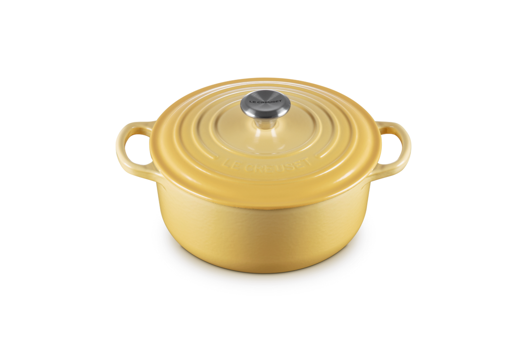 Yellow round cast iron cookware with lid on a white background