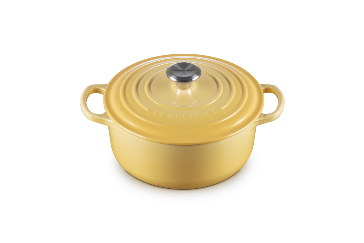 Yellow round cast iron cookware with lid on a white background