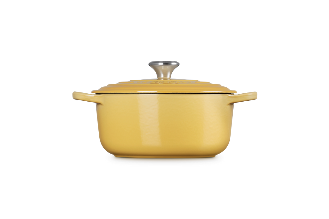 Yellow enameled cast iron Dutch oven with lid on a white background