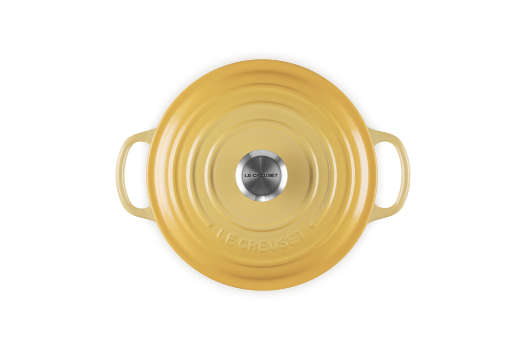 Yellow round cast iron cookware with handles on a white background