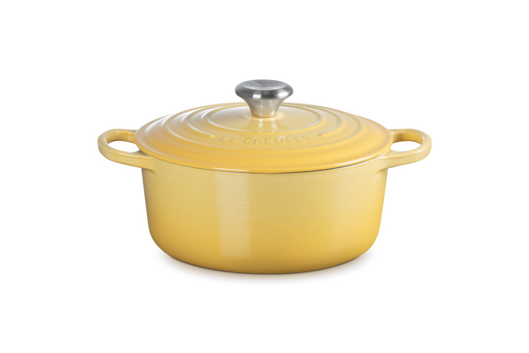 Yellow enameled cast iron cookware pot with lid on a white background