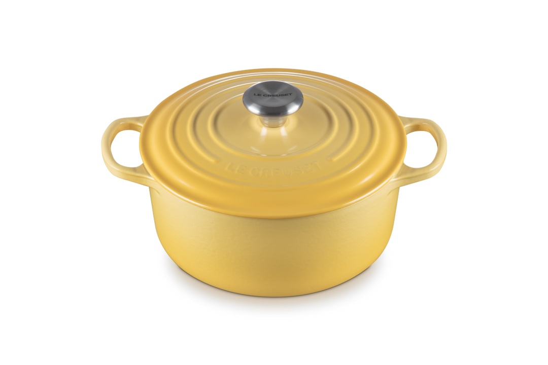 Yellow enameled cast iron Dutch oven with lid on a white background