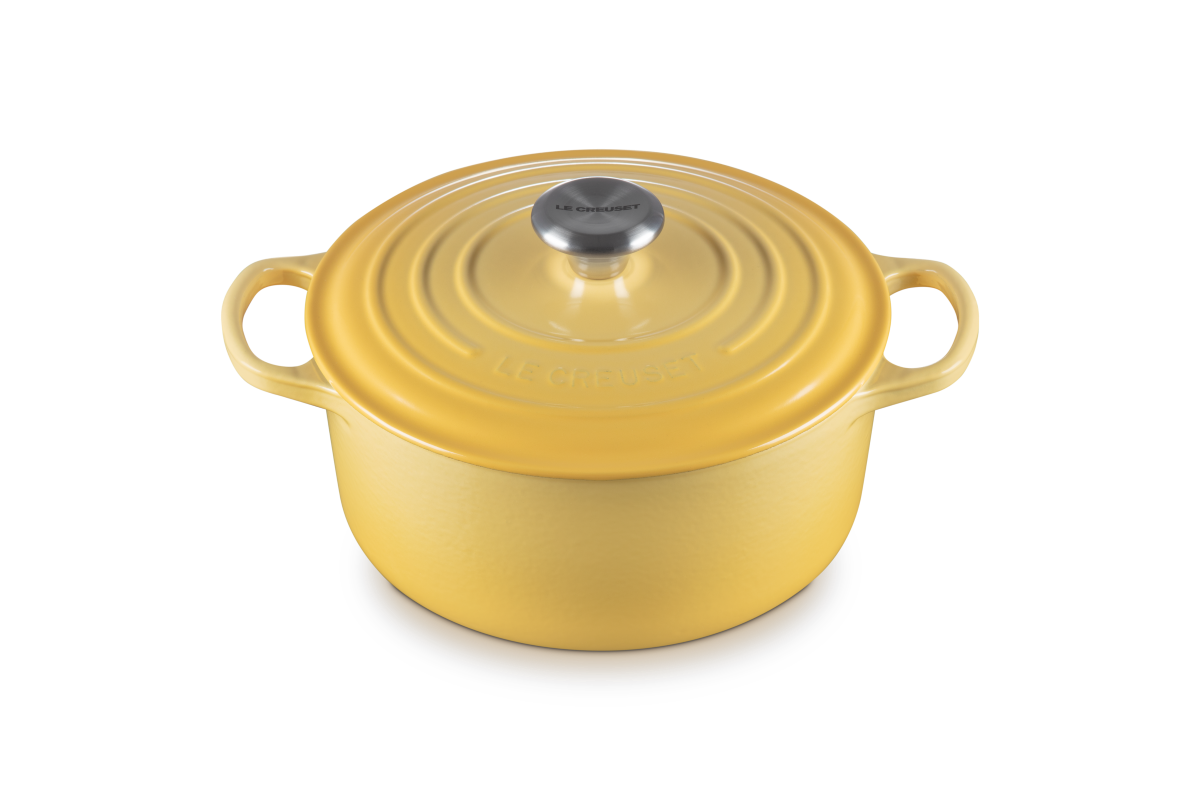 Yellow enameled cast iron Dutch oven with lid on a white background