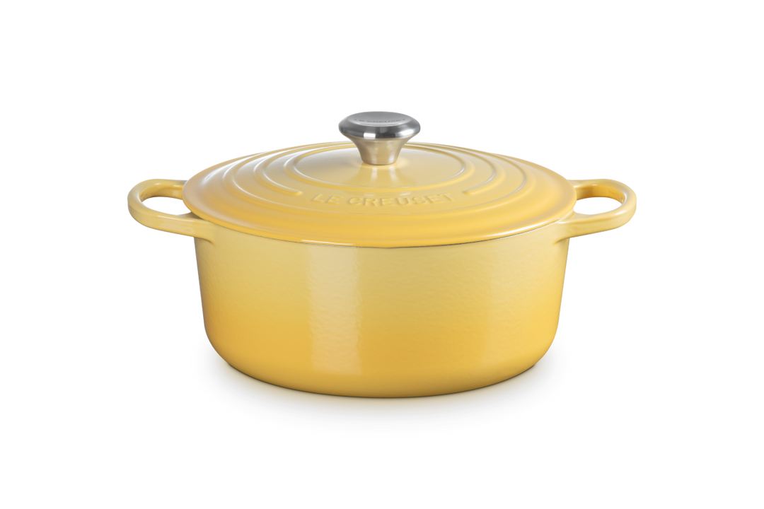 Yellow enameled cast iron Dutch oven with a lid on a white background