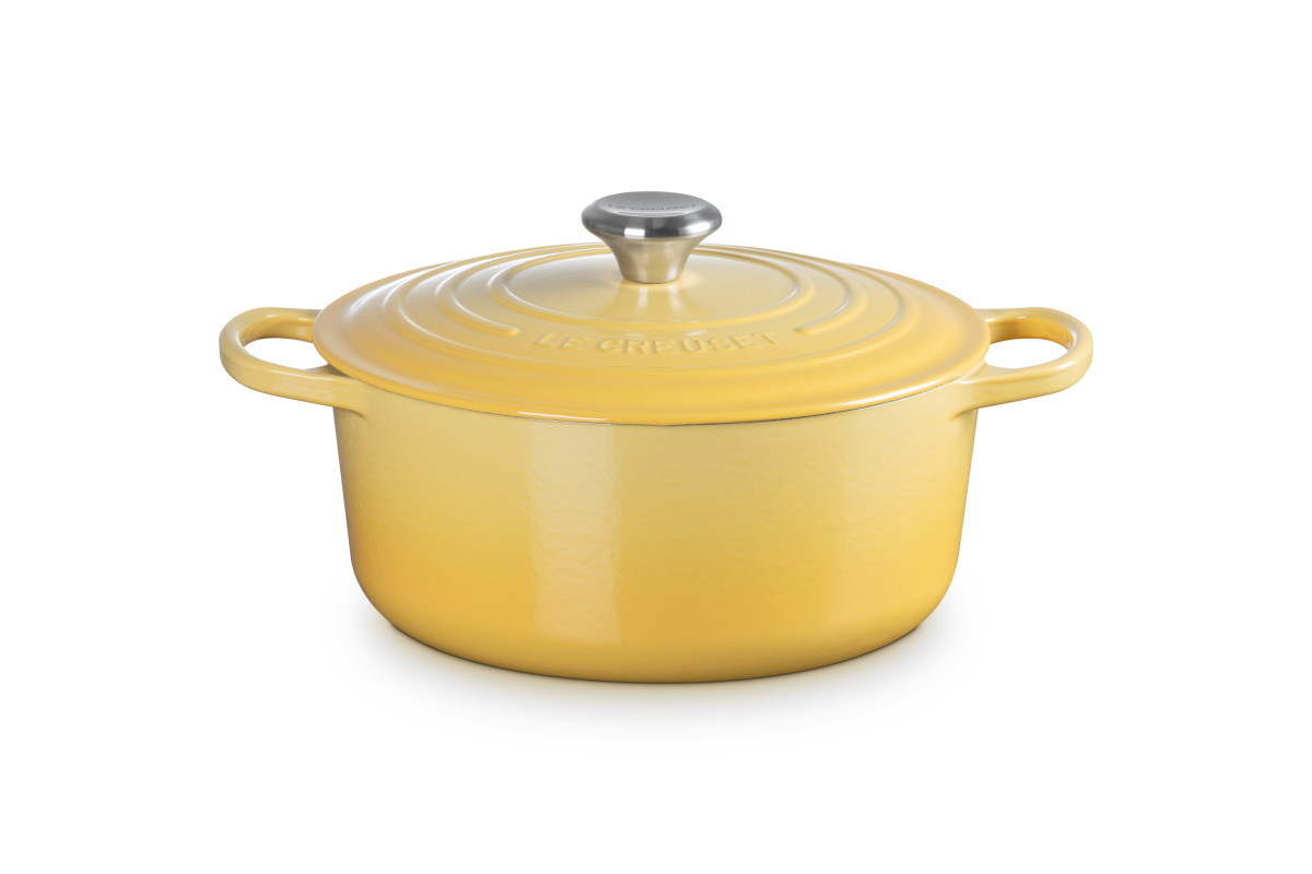 Yellow enameled cast iron Dutch oven with a lid on a white background