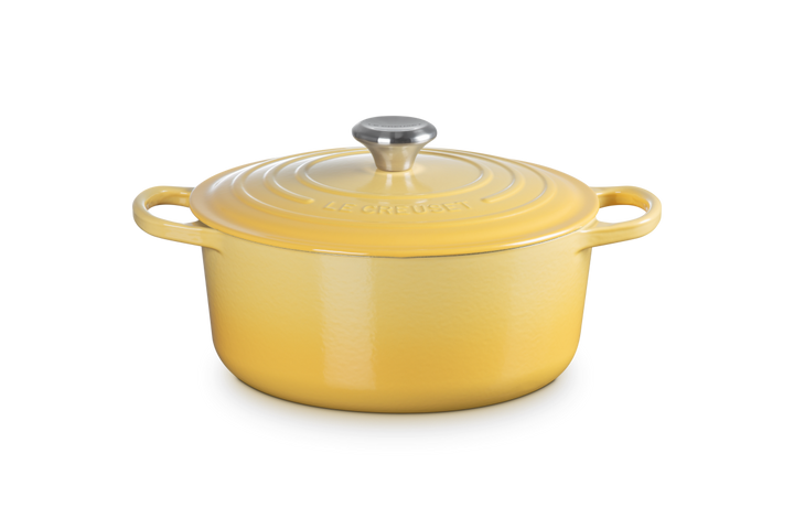 Yellow enameled cast iron Dutch oven with a lid on a white background