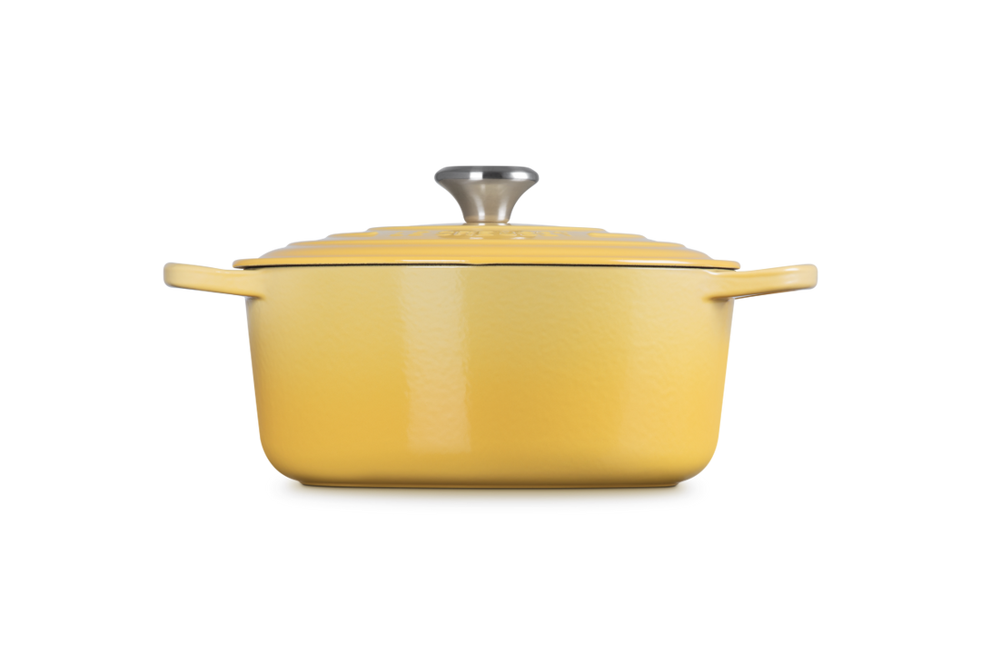 Yellow enameled cast iron Dutch oven with lid on a white background