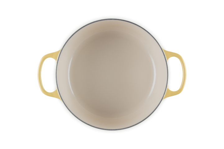 Beige enameled cast iron cookware with yellow handles on a white background