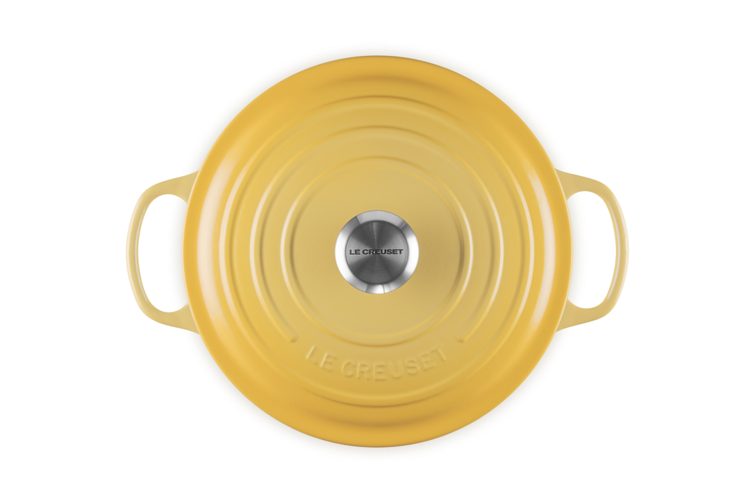 Yellow round Le Creuset french oven on a white background