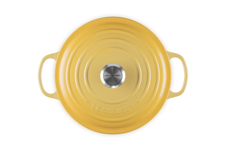 Yellow round Le Creuset french oven on a white background